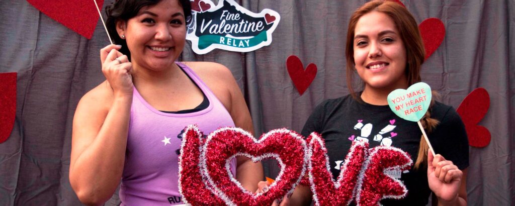 Two participants of the Fine Valentine Relay hold up heart decorations.