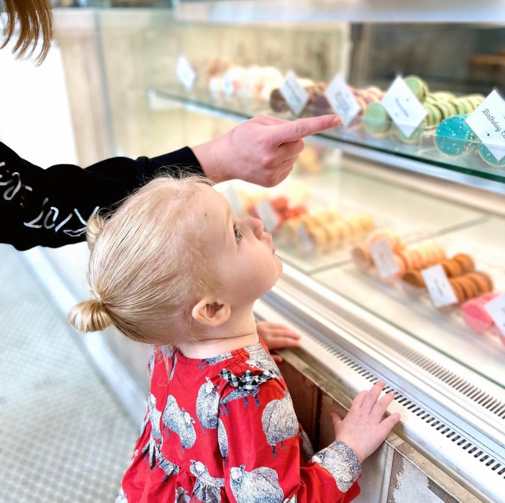 A little girl examines macarons at Woops BakeShop.