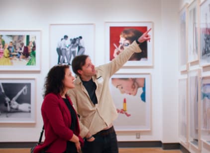 a man and woman standing looking at art on the wall